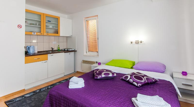 Apartment Studio 2, view at double bed, fully equipped kitchen, stove, refrigerator, kettle.