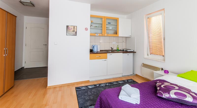 Apartment Studio 2, view at double bed, fully equipped kitchen, stove, refrigerator, kettle.